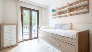 A bedroom with a bed, a dresser, a window with curtains, and built-in shelves. - Holiday Home 'Nostra' with Mountain View, Private Pool and Wi-Fi (Cas Català)