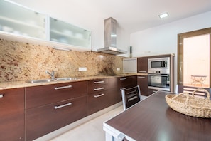A modern kitchen with granite countertops, stainless steel appliances, and dark cabinetry.