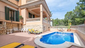 A pool area with a stone wall, yellow lounge chairs, and a covered patio. - Holiday Home 'Nostra' with Mountain View, Private Pool and Wi-Fi (Cas Català)
