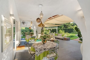 An outdoor patio area with tables and chairs, a sofa, and potted plants.