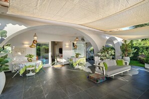 An open-plan living area with a dining table, chairs, a sofa, and a large potted plant.