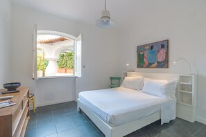 A bedroom with a bed, a desk with a bowl, a chair, a painting, and a window. - Villa 'Di Charme Ischia Porto' with Shared Terrace, Wi-Fi and Air Conditioning (Ischia)