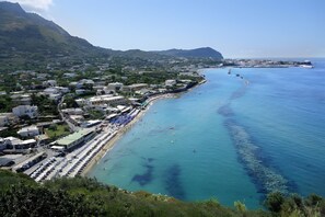 A coastal town with a beach, buildings, and a mountain in the background. - Villa 'Di Charme Ischia Porto' with Shared Terrace, Wi-Fi and Air Conditioning (Ischia)