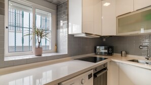 Een moderne keuken met een inbouwvaatwasser, een magnetron en een raam met een bloempot.