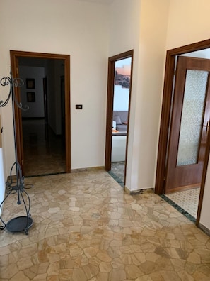 Un corridoio con pavimento in pietra, porte in legno e una rastrelliera metallica.