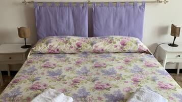 Un letto con biancheria da letto floreale, due comodini e una parete decorata con cuori.