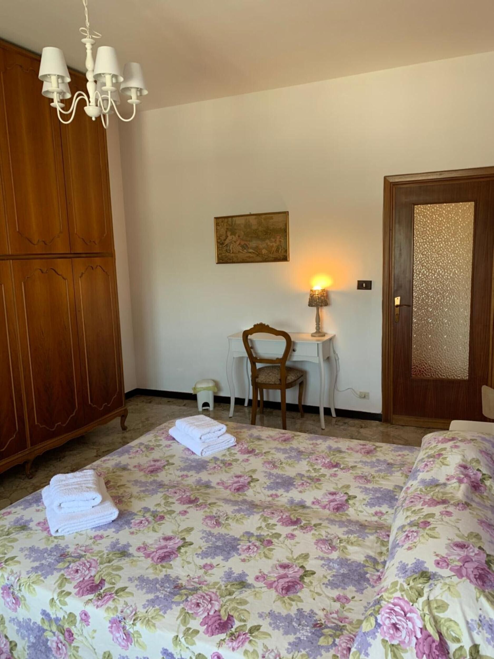 Une chambre à coucher avec un lit, un bureau, une chaise, une armoire et un tableau accroché au mur.