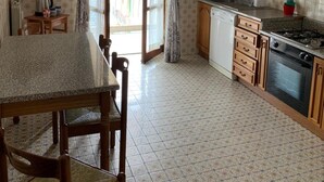 A kitchen with a dining table, chairs, a stove, and a sink. - Apartment 'Serravalle Shopping' with Balcony and Wi-Fi (Serravalle Scrivia)