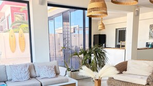 Una sala de estar moderna con un sofá, una mesa de centro y un amplio ventanal con vistas a palmeras.