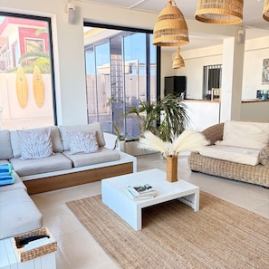 A modern living room with a sofa, coffee table, and a large window with a view of palm trees. - Valencia Vacation Home with Sea Views, Private Pool & Wi-Fi (Santa Cruz de Tenerife)