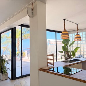 A modern kitchen with a large window, a fan, and hanging pendant lights.