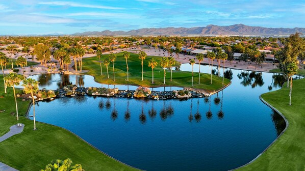 Golfers can enjoy a serene round amidst manicured lawns, palm trees, and scenic mountain views.