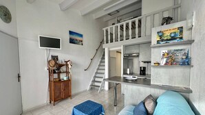 Een compacte leefruimte met kitchenette, een eethoek en een trap naar een hoger gelegen niveau.