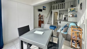Een compact woongedeelte met een eethoek, een kitchenette en een trap naar een hoger gelegen niveau.