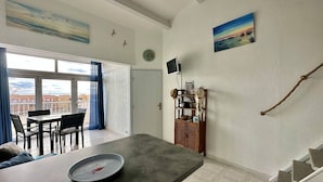 Een ruime woonkamer met een balkon, een eettafel en uitzicht op de stad.