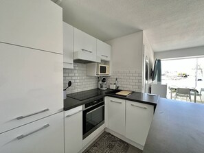 Een koelkast, een microgolfoven, een oven, kookgerei, borden en bestek