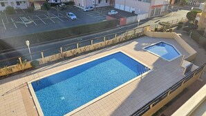A rooftop pool with a view of a parking lot and buildings in the background.