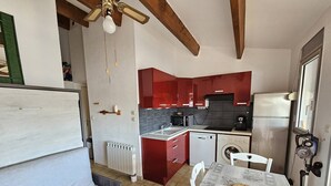 A compact kitchen with red cabinets, a built-in oven, a microwave, and a refrigerator.