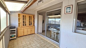 A compact kitchen with a wooden cabinet, a small table, and a sliding glass door leading to a balcony.
