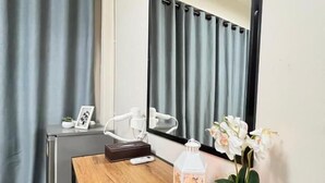 Una habitación pequeña con un escritorio de madera, un espejo, una planta en maceta y un farol decorativo.