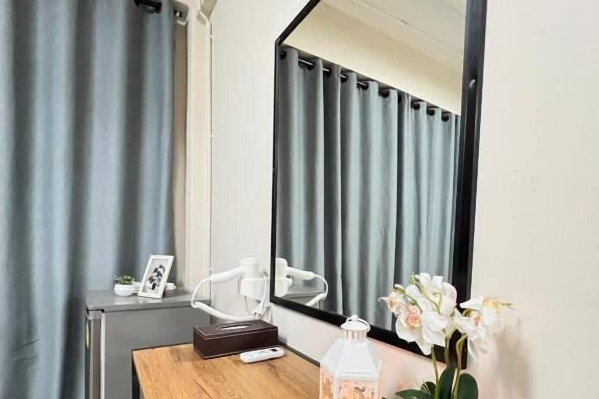 Une pièce de taille modeste, avec un bureau en bois, un miroir, une petite plante en pot et une lanterne décorative.