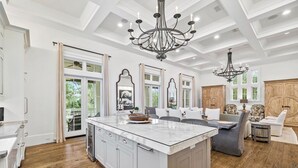 A spacious kitchen with a large island, wooden cabinets, and a chandelier. - Across from Sand Hill Circle Frog Pool - Golf Cart -5BR/5.5BTH Watercolor Home (Santa Rosa Beach)