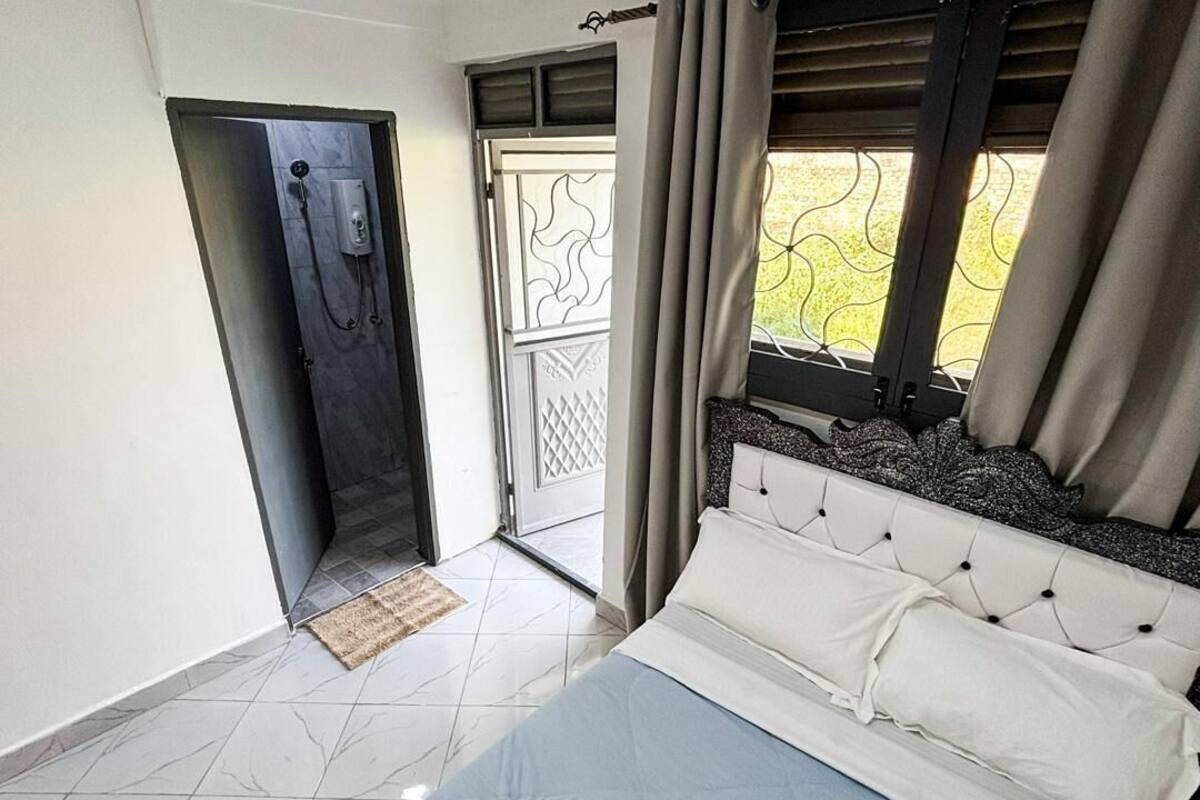 A bedroom with a bed, a door leading to a balcony, and a window with curtains.