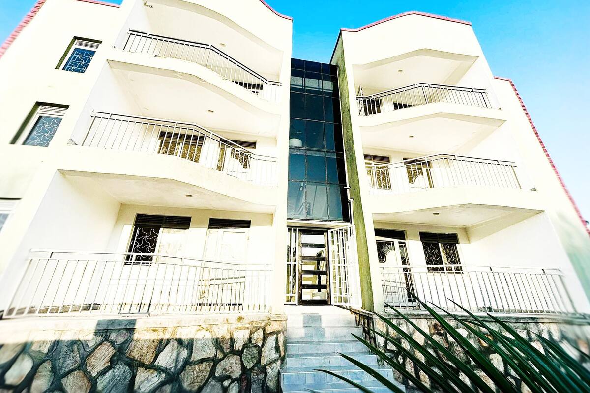 A modern two-story building with balconies, a central entrance, and a stone staircase leading up to the entrance.