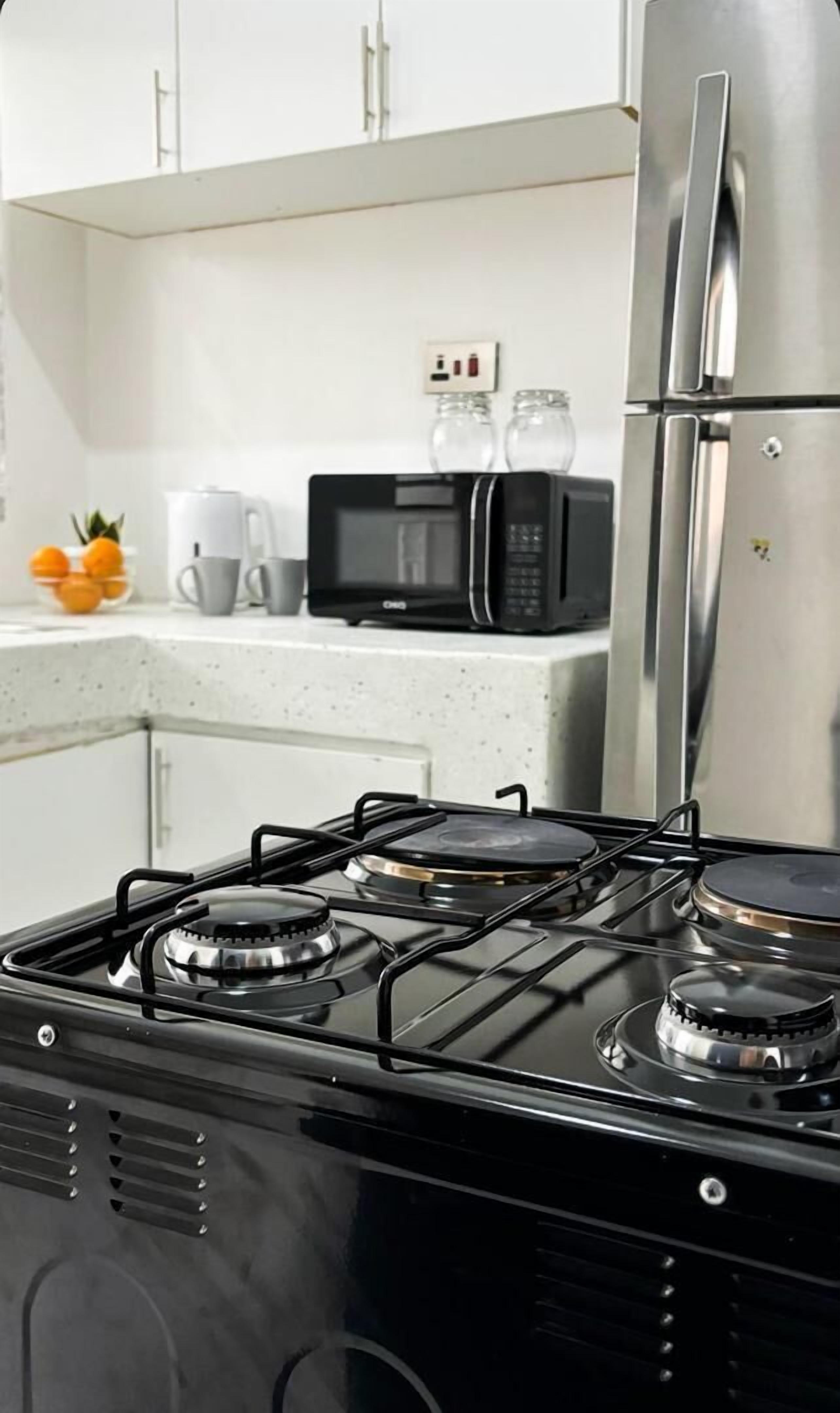 A kitchen with a black stove, a microwave, and a stainless steel refrigerator.