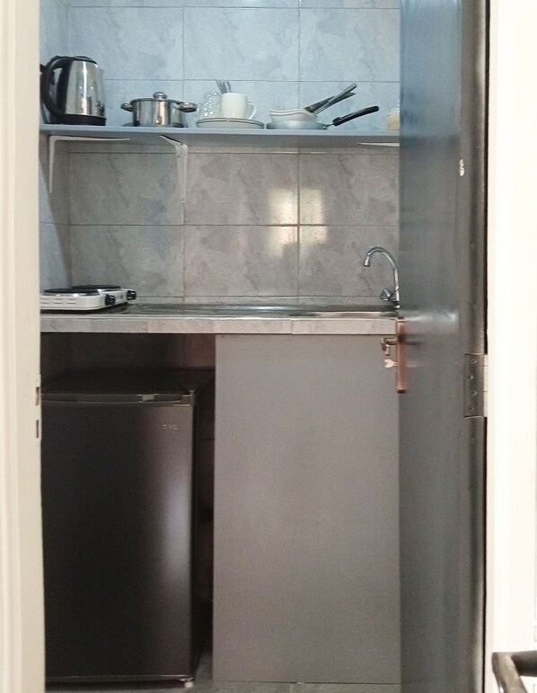A compact kitchen with a sink, a kettle, a pot, and a toaster. - Dutus ApartHotel Entebbe (Entebbe)