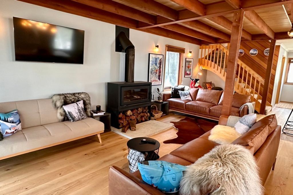 Ein gemütliches Wohnzimmer mit Kamin, Ledersofas und einer Holztreppe.