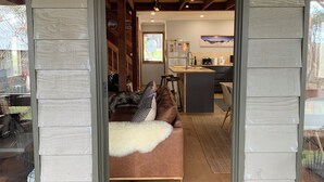 A cozy living room with a brown sofa, a white furry throw, and a black doormat. - Cuff'n'Collar Stable Chalet (Dinner Plain)
