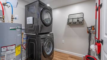 A laundry room with stacked washers and dryers, a water heater, and a wall-mounted toolbox.