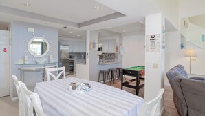 A modern kitchen with a central island, a dining area with a striped tablecloth, and a pool table. - 357 Ocean View (Pismo Beach)