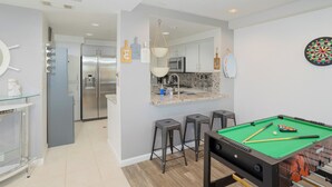 A modern kitchen with a central island, bar stools, and a pool table. - 357 Ocean View (Pismo Beach)
