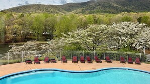 A swimming pool with red lounge chairs and a view of a lake and mountains. - Cozy cabin and TUBING!  Swim, Horses, hiking, lake-3 mi from Helen! Relax!  (Cleveland)