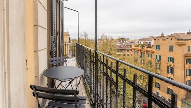 Ein Balkon mit Tisch und Stühlen mit Blick auf eine Stadtlandschaft und Gebäude.