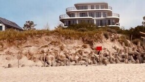 Ein Strandgrundstück mit einem gebogenen, mehrstöckigen Haus.