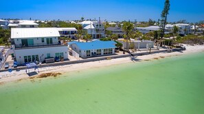 A coastal property with a large building featuring multiple rooms and a covered outdoor area with seating.