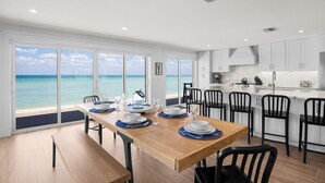 A modern kitchen with white cabinets and a dining area with a wooden table set for four.