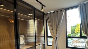 A hotel room with a bed, a wardrobe, a window with curtains, and a view of the outside. - Studio with pool in downtown RJ (Santa Teresa Rio de Janeiro)