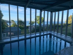 An indoor swimming pool with a view of the sea and surrounding greenery. - Cottage with 3 bedrooms - sea view (PLOUHA)
