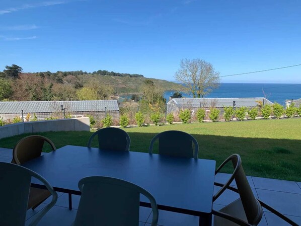 A patio with a table and chairs overlooking a coastal view. - Cottage with 3 bedrooms - sea view (PLOUHA)