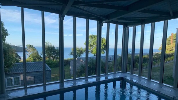 Ein Innenpool mit Blick auf das Meer und die grüne Umgebung.