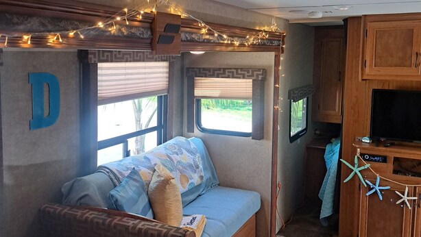 A cozy RV interior with a bunk bed, a small kitchenette, and a TV. - Cozy River Retreat 2-bedroom RV with AC, in Homosassa Springs , FL
Lot D15 (Homosassa)