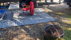 A recreational vehicle with a covered dining area, a fire pit, and a red folding chair. - Cozy River Retreat 2-bedroom RV with AC, in Homosassa Springs , FL
Lot D15 (Homosassa)