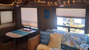 A cozy RV interior with a sofa, a small table, and a window with blinds. - Cozy River Retreat 2-bedroom RV with AC, in Homosassa Springs , FL
Lot D15 (Homosassa)