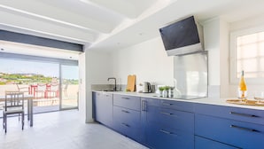 A modern kitchen with blue cabinets, a stainless steel sink, and a flat-screen TV mounted above the counter.