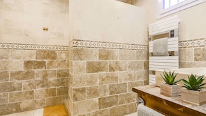 A bathroom with stone walls, a wooden vanity, a mirror, and a window.