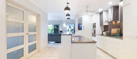 A modern kitchen with white cabinetry, a central island, and a dining area visible in the background.